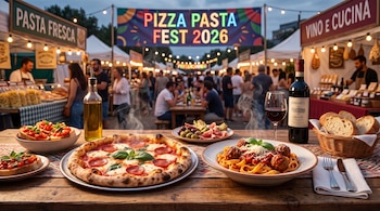 Una mesa con pizza, pasta y vino frente a un festival al aire libre con un cartel que dice Pizza Pasta Fest 2026.