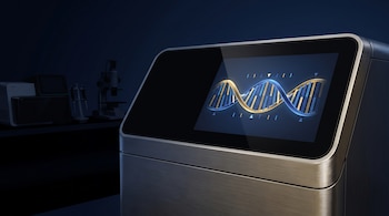 Dispositivo metálico de laboratorio con pantalla encendida que expone una cadena de ADN iluminada sobre un fondo en penumbra con microscopio.