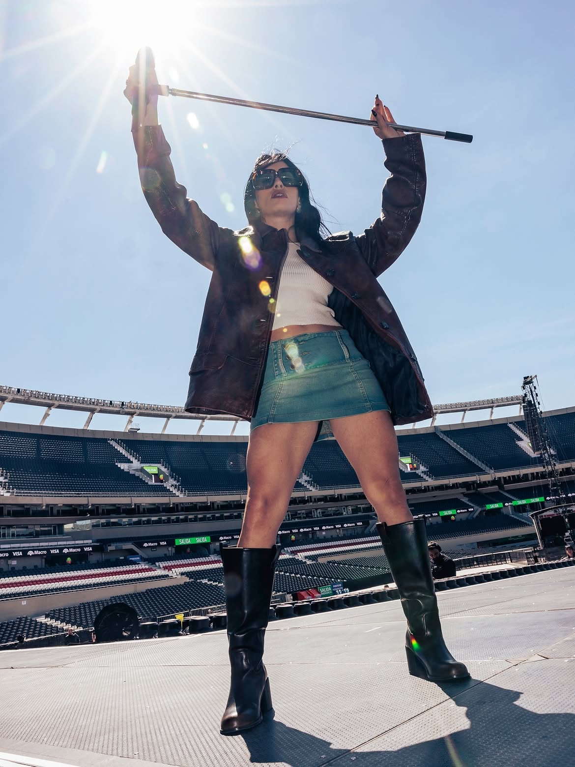 En contrapicado y con el sol de fondo, la cantante levanta el palo del micrófono sobre el escenario vacío que esta noche recibirá a más de 80.000 personas