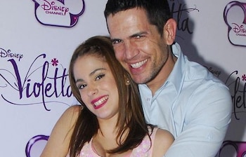 Diego Ramos y Tini Stoessel sonríen para la cámara, él la abraza. Están frente a un fondo blanco con los logotipos morados de Disney Channel y Violetta