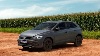 Automóvil Volkswagen Polo Robust gris oscuro estacionado sobre un camino de tierra. Al fondo, un campo de maíz bajo un cielo azul con nubes