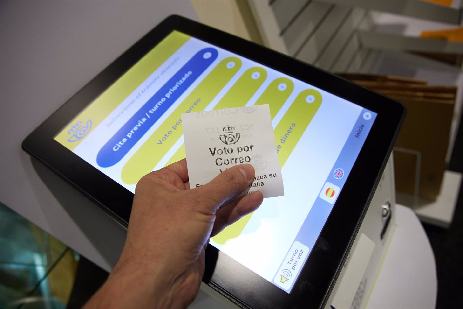 Una persona con un ticket de voto por correo en una oficina de Correos. (Jesús Hellín/ Europa Press)