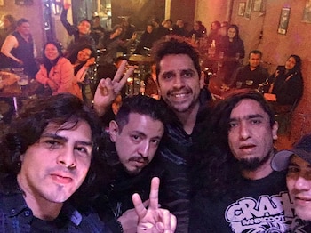 Cinco hombres posan para un autorretrato en el interior de un bar con varios clientes sentados al fondo