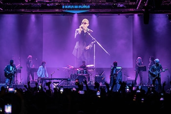 Concierto de Los Fundamentalistas Del Aire Acondicionado en un escenario con luces moradas. Una pantalla gigante proyecta a Indio Solari. El público, con móviles, anima