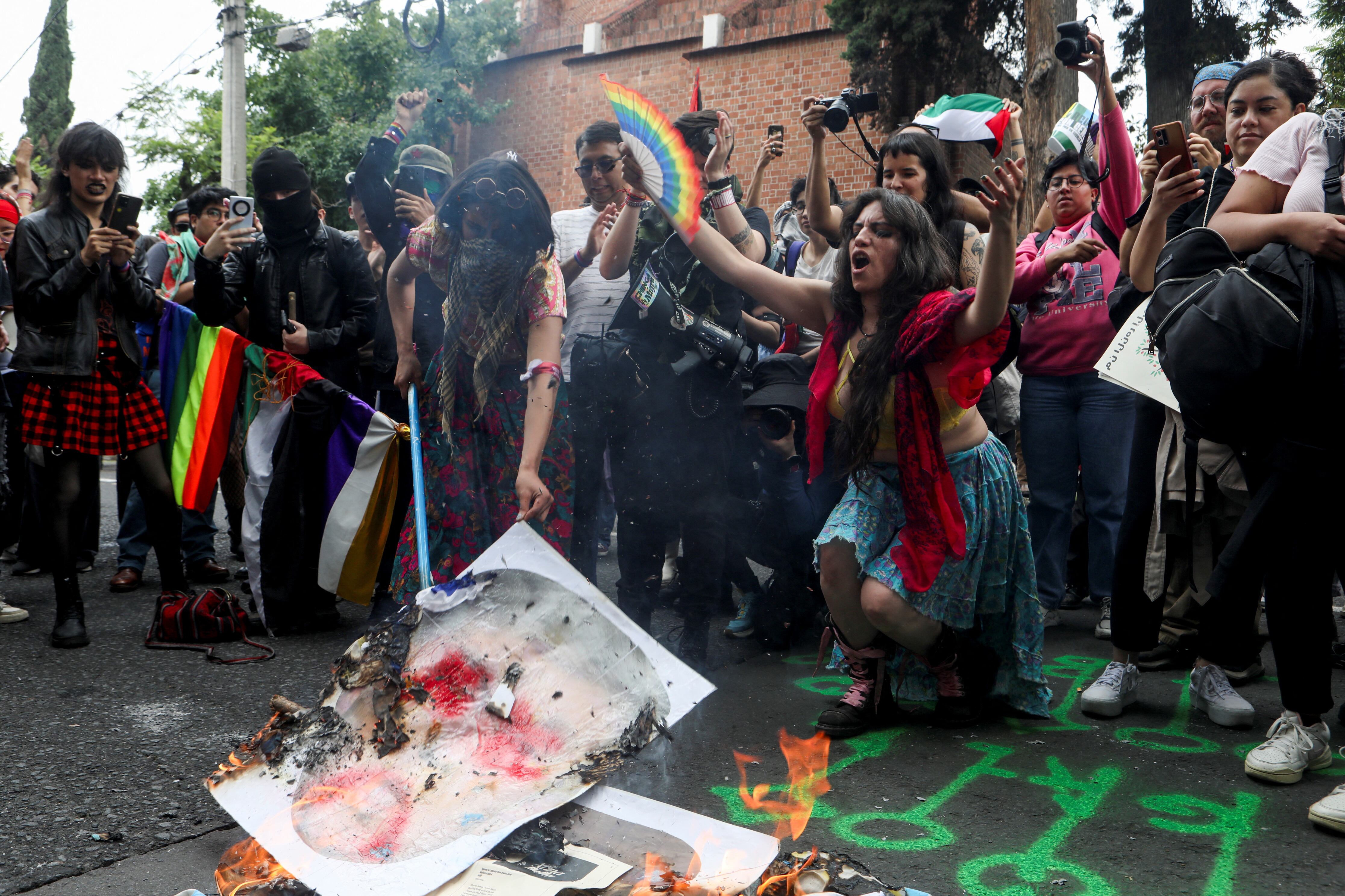 People burn an image of U.S. President Donald Trump during the