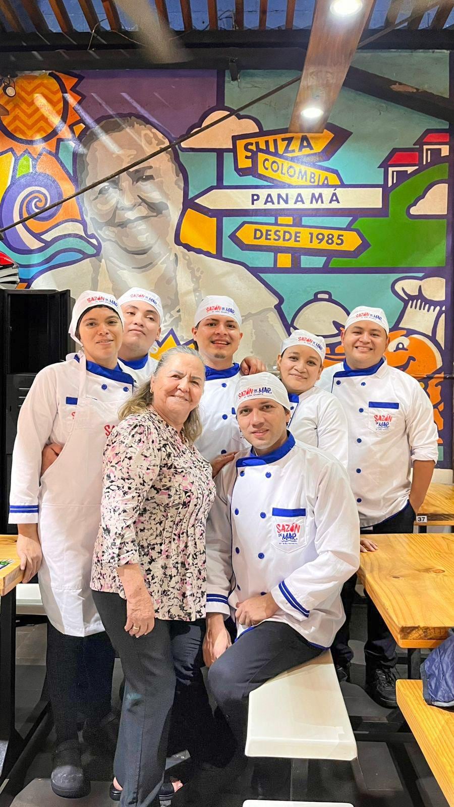 Maurita, quien posa con un grupo de colaboradores, ha sido la figura clave del negocio familiar de venta de mariscos preparados. En los locales de Sazón del Mar está inmortalizada en sus paredes. Foto Infobae Centroamérica/Cortesía Familia Mauritas López