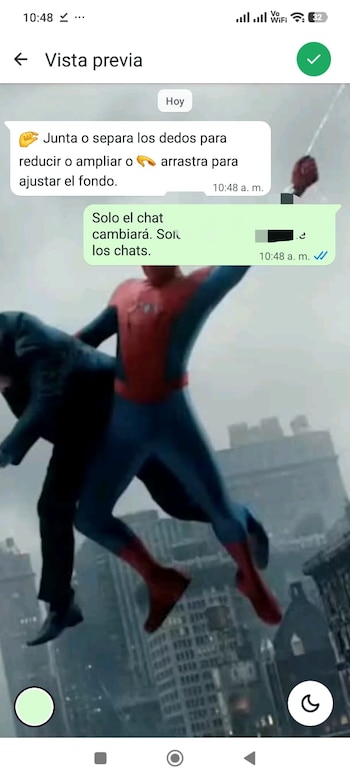 Pantalla de teléfono con interfaz de chat. Spider-Man con traje rojo y azul carga a una persona con traje oscuro sobre una ciudad con edificios