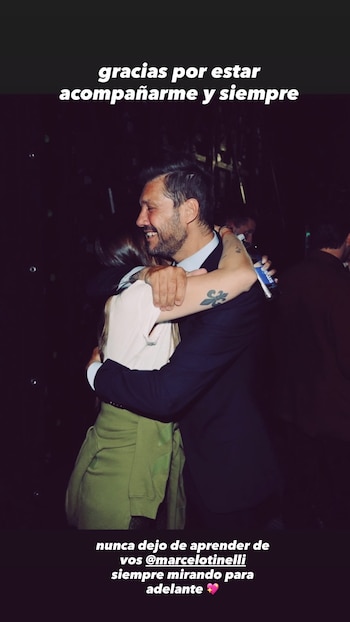 Marcelo Tinelli, un hombre con barba y un tatuaje en el brazo, abraza sonriente a una mujer de cabello largo y camisa clara en un ambiente oscuro