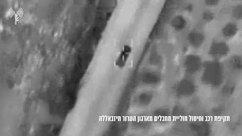 Vista aérea en blanco y negro con mira digital sobre un vehículo pequeño en una carretera; fondo borroso con áreas oscuras y claras