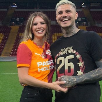 Mauro Icardi y China Suárez sonríen en un campo de fútbol. Ella con camiseta de Galatasaray, él con camiseta negra y número 26. Se toman de la mano