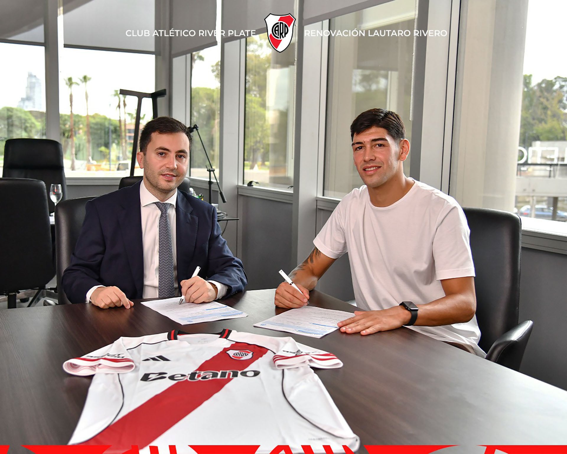 Lautaro Rivero firma su renovación de contrato junto a un representante del Club Atlético River Plate, con la camiseta oficial del equipo visible sobre la mesa. (@RiverPlate)