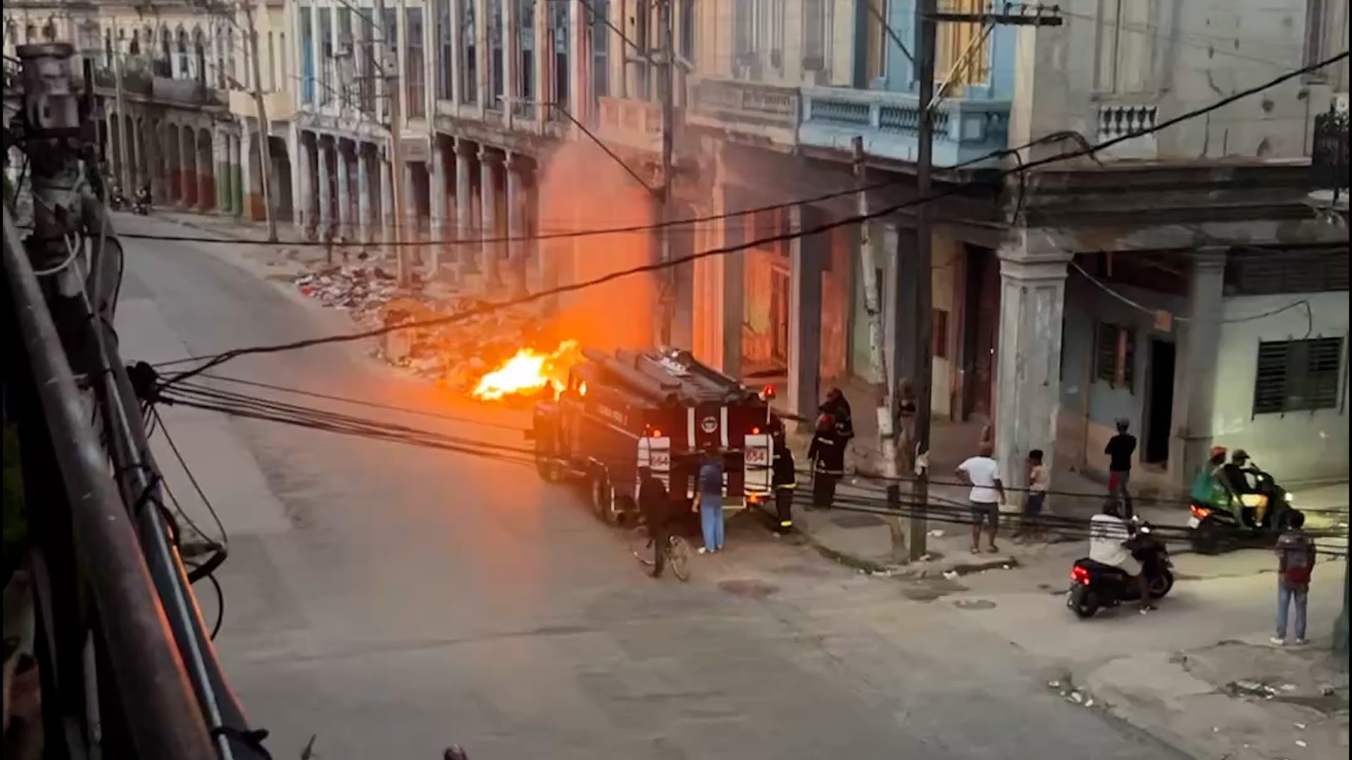 Bomberos de La Habana combaten un incendio de basura en una calle céntrica, mientras varios residentes observan la escena (Captura)