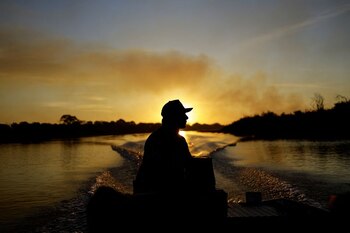 El guía de pesca Amilton Brandao navega por el río Paraguay mientras el humo se eleva en el aire por el incendio en el Pantanal (REUTERS/Ueslei Marcelino)