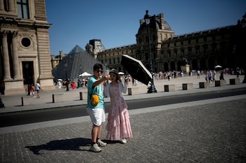 Turistas usan un paraguas para protegerse del sol en París, el 22 de junio de 2026, durante la intensa ola de calor que afecta a Francia. (Foto AP/Christophe Ena)