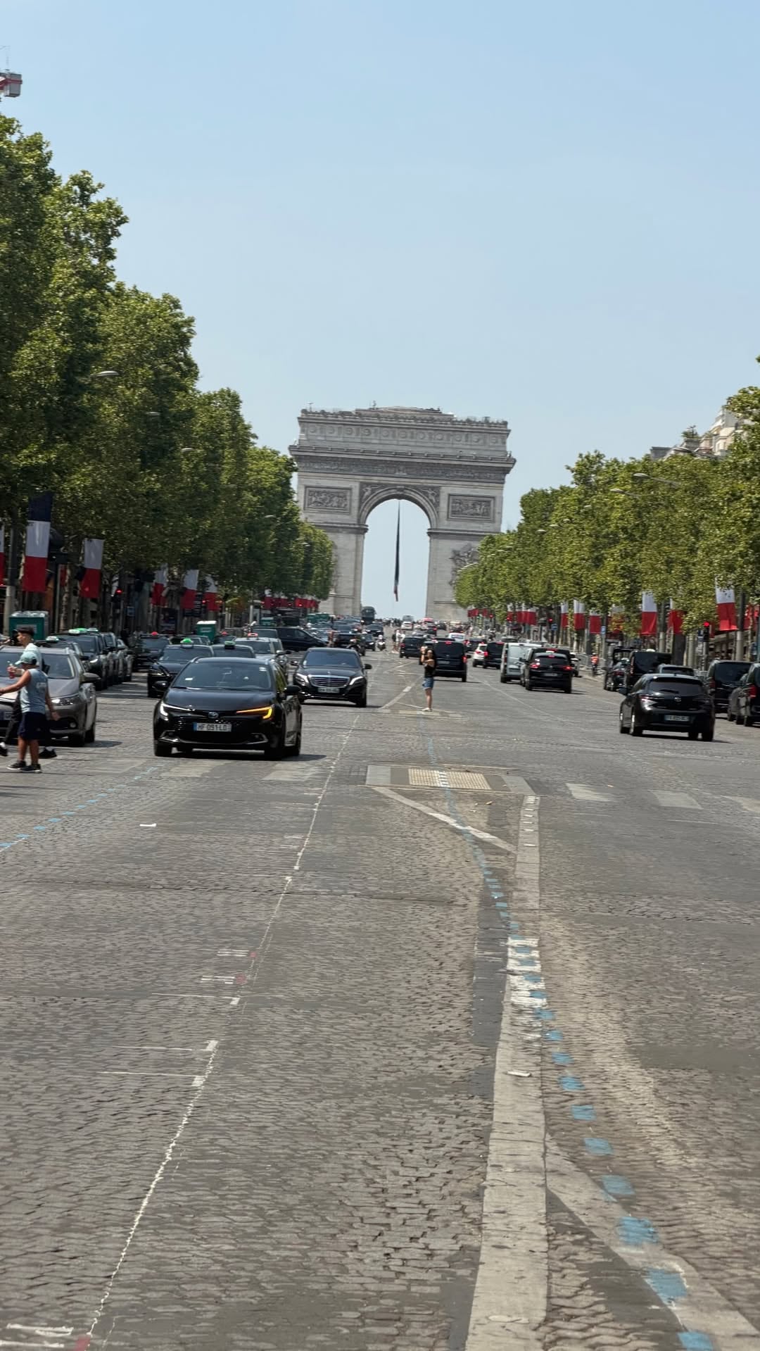 Vista de la Avenida de los Campos Elíseos con el Arco de Triunfo al fondo, adornado con banderas francesas durante las celebraciones del 14 de julio