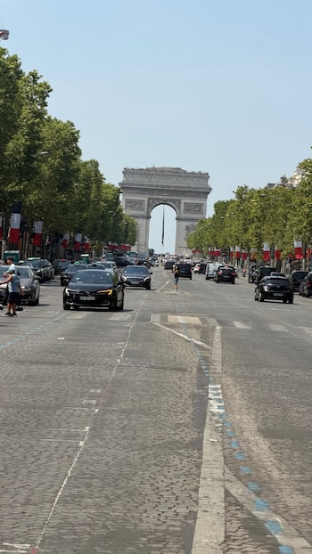 Vista de la Avenida de los Campos Elíseos con el Arco de Triunfo al fondo, adornado con banderas francesas durante las celebraciones del 14 de julio