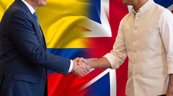 Dos hombres sin rostro visible estrechan sus manos con las banderas de Colombia y el Reino Unido de fondo.