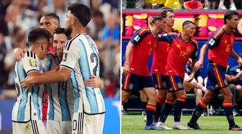 Jugadores de Argentina con camiseta celeste y blanca celebran, y jugadores de España con camiseta roja y pantalón azul caminan en el campo.