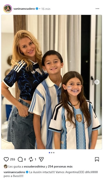 Mujer rubia de jeans y camiseta deportiva azul con diseño negro posa sonriendo junto a un niño y una niña con camisetas de fútbol argentinas