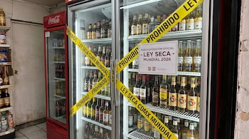 Dos refrigeradores comerciales llenos de botellas de bebidas alcohólicas están cruzados con cinta amarilla de "Prohibido Ley Seca CDMX Mundial", y un letrero indica la disposición oficial.