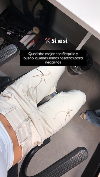 Vista desde arriba de una persona con pantalón blanco que tiene mechones de cabello sobre las piernas