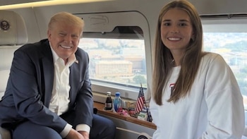 Donald Trump de traje y Kai Trump con sudadera blanca sonríen dentro de un avión frente a una ventanilla
