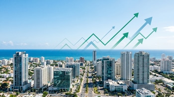 Vista panorámica aérea de Santo Domingo con edificios modernos y el mar Caribe al fondo. Sobre el cielo, gráficos ascendentes en tonos verde y azul que sugieren crecimiento.