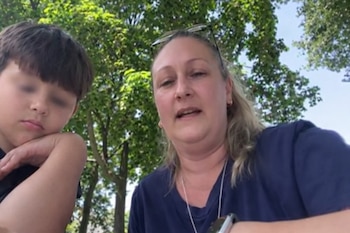 Una mujer de cabello rubio con anteojos en la cabeza y un niño con ojos borrosos aparecen en un primer plano. Detrás se ven árboles y cielo azul. Fiebre del conejo
