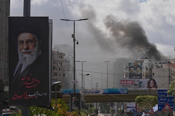 Imagen de un retrato de Ali Khamenei con columnas de humo elevándose en el distrito de Dahiyeh, en Beirut (AP/Archivo)