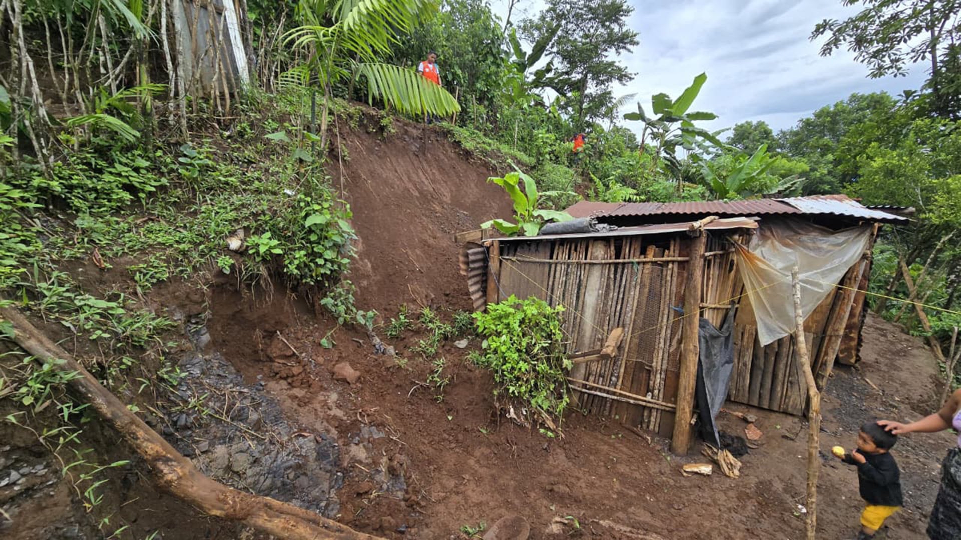 Un deslizamiento de tierra, provocado por las recientes lluvias torrenciales, amenaza una vivienda precaria en una zona rural de Guatemala, mientras equipos de rescate evalúan la situación. (SE CONRED Guatemala)