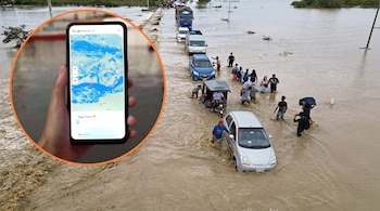 Mano sostiene teléfono con Google Flood Hub mostrando mapa y "Niger River". Carretera anegada con personas, vehículos y árboles sumergidos en agua