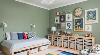 Dormitorio infantil con paredes verdes, cama de madera con ropa de cama a rayas, cojines de Buzz Lightyear. Muebles de madera con cajones organizadores, reloj de pared y cuadros.
