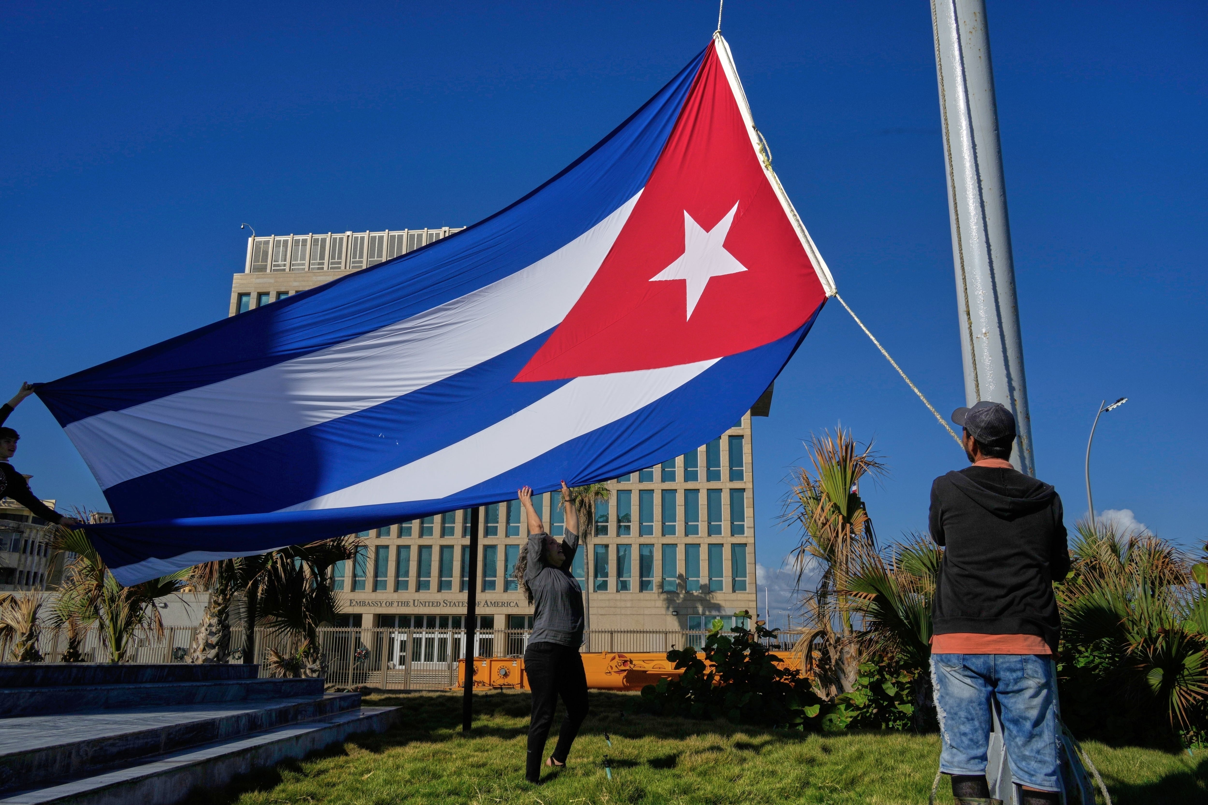 Trabajadores ondean la bandera cubana a media asta en la Tribuna Antiimperialista, cerca de la embajada de Estados Unidos en La Habana, Cuba, el lunes 5 de enero de 2026, en memoria de los cubanos fallecidos dos días antes en Caracas, Venezuela, durante la captura de Nicolás Maduro por fuerzas estadounidenses.(Foto AP/Ramón Espinosa)