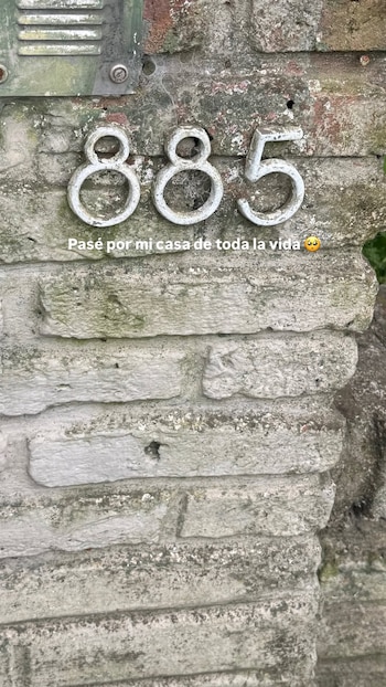 Números de metal 885 en una pared de ladrillos grises con musgo y una caja metálica. El texto dice: 'Pasé por mi casa de toda la vida 🥺'