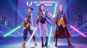 Tres figuras femeninas estilizadas sostienen sables de luz de colores sobre un escenario futurista frente al texto Las Guerreras del Sable