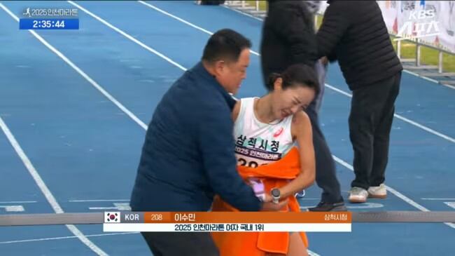 El entrenador Kim Wan-ki abraza con una toalla a la atleta coreana Lee Su-min (captura video)