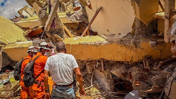 Rescatistas salvadoreños inspeccionan una estructura colapsada junto a un hombre que busca a su hijo tras los terremotos en La Guaira, Venezuela (Cortesía Secretaría de Prensa).