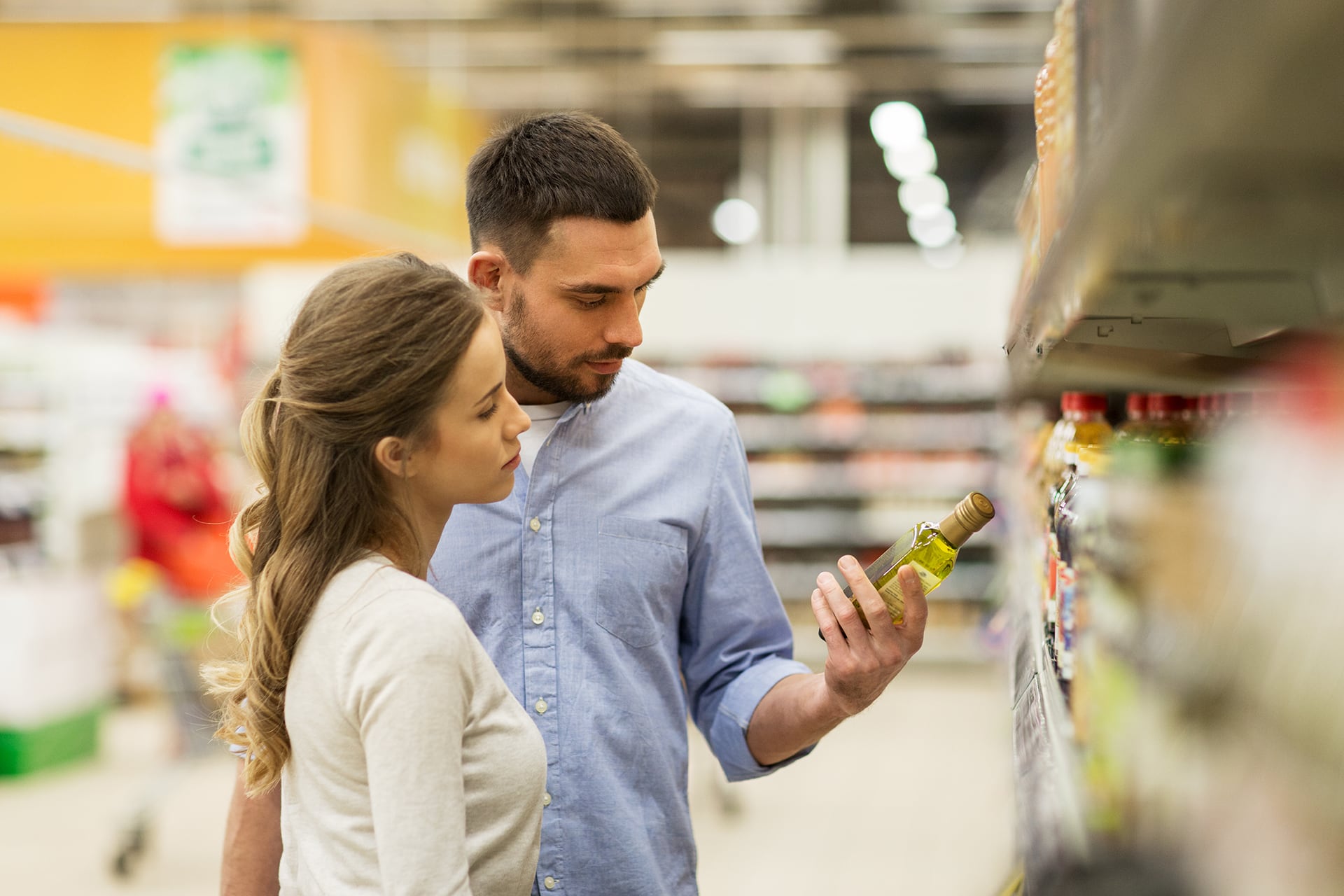 Una pareja lee el etiquetado de una botella de aceite de oliva en un supermercado. (Freepik)