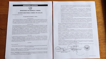 Documento oficial del Ministerio de Energía y Minas de Guatemala con texto impreso, sellos y firmas sobre una superficie de madera.