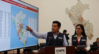 Dos trabajadores de la ONPE presentan resultados electorales en una pantalla grande con el mapa de Perú. Al fondo, un mapa mural de Perú.