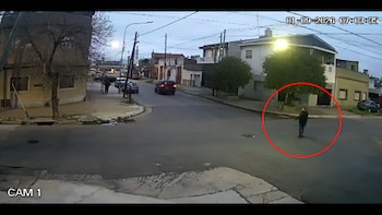 Captura de cámara de seguridad que muestra una intersección de calles, viviendas, un automóvil y una persona dentro de un círculo rojo
