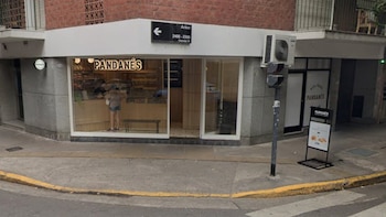 Fachada de un local con cartel de Pandanés, ventanales de vidrio iluminados, acera con cordón amarillo y cartel de la calle Aráoz
