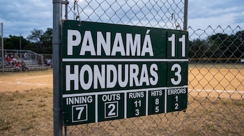 Tablero verde en una cerca de malla con las inscripciones Panamá 11 y Honduras 3, además de datos de entradas, carreras, hits y errores.