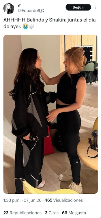 Dos mujeres, Belinda y Shakira, de pie una frente a la otra; Shakira, a la derecha, toca el hombro de Belinda. Ambas visten ropa oscura