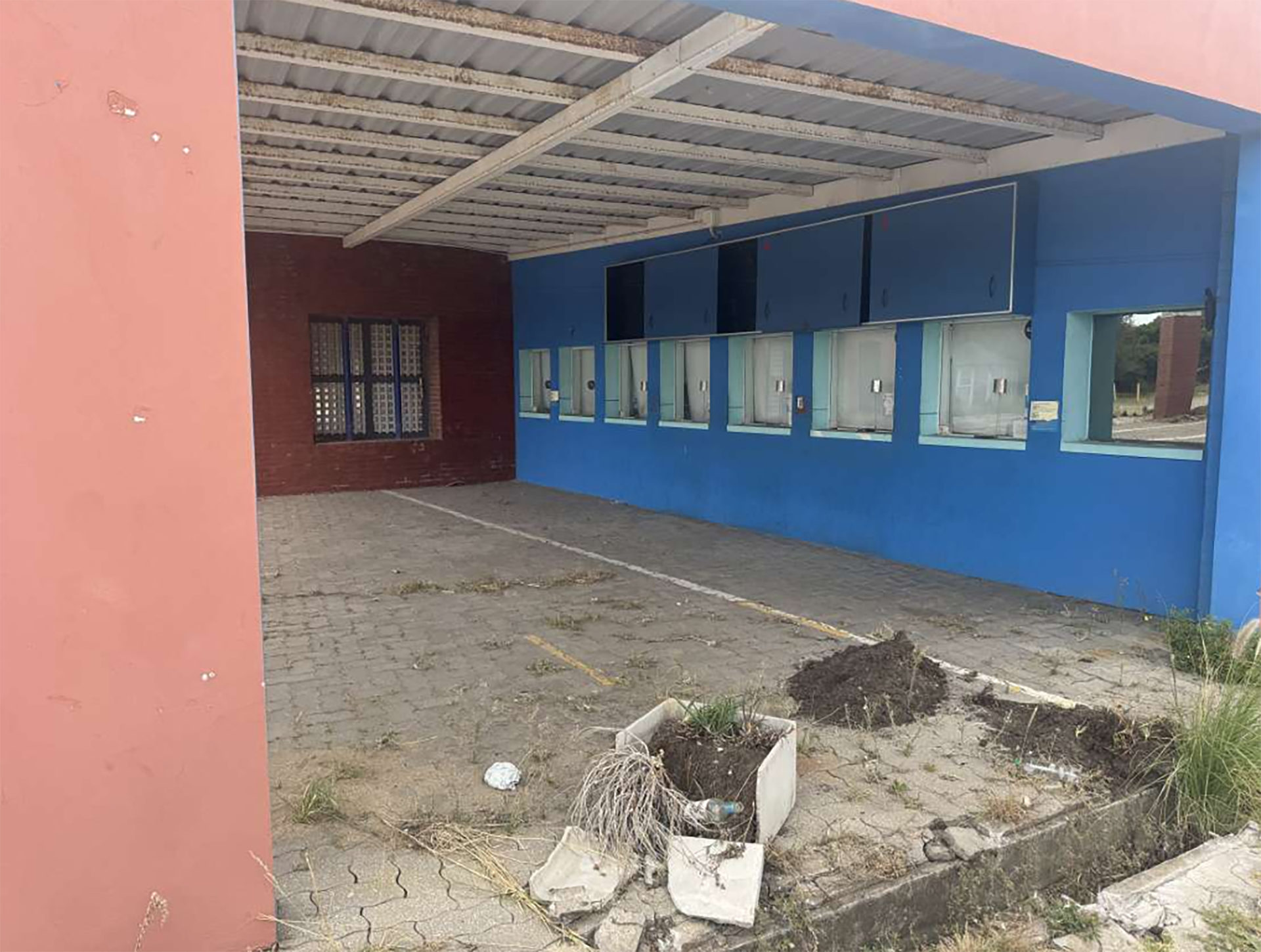 La entrada del Acuario de Mar del Plata muestra signos de abandono y deterioro, con estructuras descuidadas, paredes descascaradas y maleza invadiendo el pavimento.