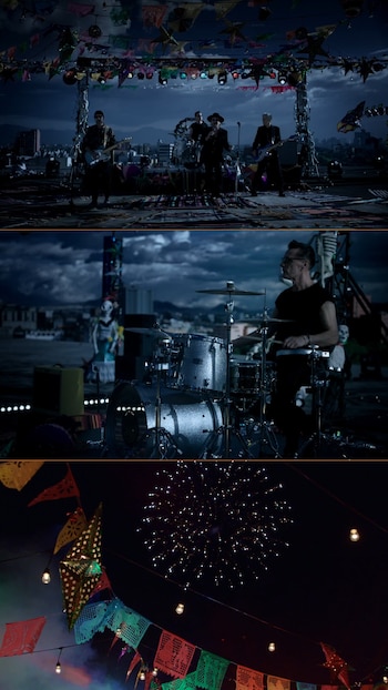 La banda U2 toca en un escenario montado en la azotea del edificio Expo Reforma, con la ciudad de fondo. El cielo nocturno está iluminado por fuegos artificiales y decoraciones festivas