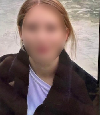Primer plano de una persona con el rostro borroso, cabello claro, pendiente en la oreja izquierda, chaqueta oscura y camiseta blanca, con un fondo claro