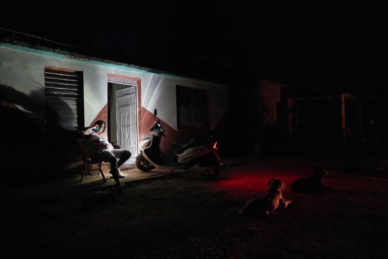 Una mujer utiliza la luz de una moto mientras habla por teléfono durante un apagón en Guanajay, Cuba. (REUTERS/Alexandre Meneghini)