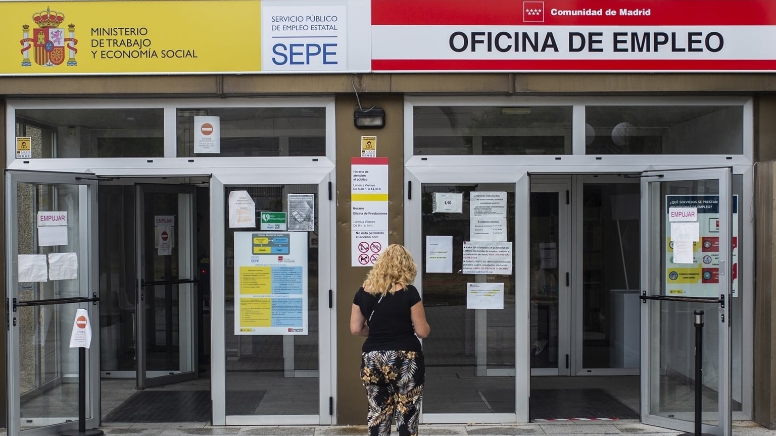 Una mujer frente a una oficina del SEPE. (Freepik)