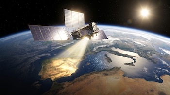 Satélite con paneles solares en el espacio, sobre la Tierra, con el sol y estrellas visibles. Un haz de luz se proyecta sobre la superficie terrestre.
